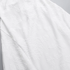 Close-up detail of white jacquard fabric with elegant butterfly and leaf patterns