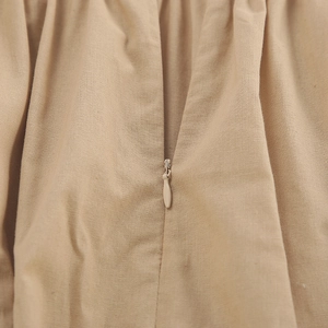 Makro-Detail des hochwertigen verdeckten Reißverschlusses am khakifarbenen Leinenkleid