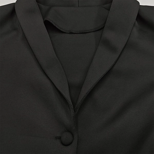 Detail view of deep V-neckline with fabric covered button on black long sleeve dress