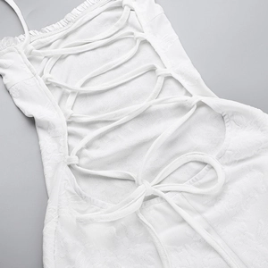 Detailed back view of white lace-up dress with floral jacquard texture and ribbon tie