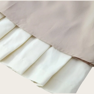Détail de l'ourlet plissé contrasté avec tissu beige lisse et plis blancs soyeux