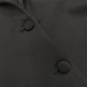 Detailed view of black deep V-neck dress with fabric-covered buttons and sewing craft