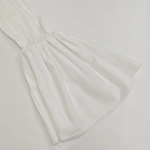 Détail de la manche cloche blanche montrant les côtes en tricot et le tissu évasé