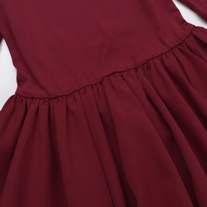 Detailed view of the pleated waist and flowing skirt hem of the burgundy dress