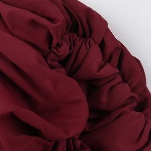 Detail of elegant wine red dress showing high-density smocked fabric and soft ruffled texture