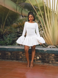 Robe blanche élégante avec manches cloches et jupe plissée dans un cadre tropical