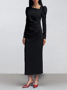 Detail shot of elegant black slim fit dress with asymmetric neckline and puffed sleeves