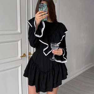 Detail of elegant black mini dress featuring white lace ruffles and flared sleeves