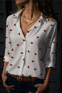 Detail of white long sleeve shirt with red heart prints and button-up lapel collar