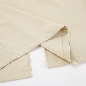 Detail of the side slit hem on a beige dress showing high-quality woven fabric texture