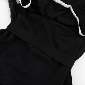 Detail of black dress featuring delicate white lace trim and sleek woven fabric texture