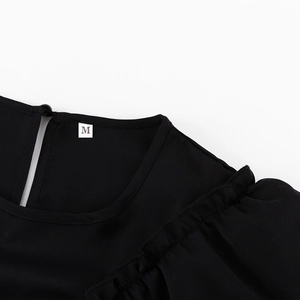 Close-up of a black dress neckline with ruffle shoulder details and M size label