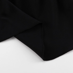 Close-up of the smooth hem stitching and black polyester fabric texture on a flared dress