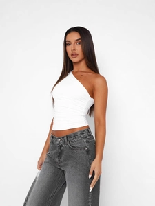White one-shoulder slim fit tank top with side ruching paired with grey jeans