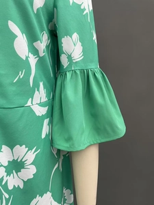 Detailed view of the ruffle cuffs and white floral print on a green summer dress