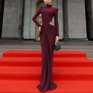 Robe longue rouge vin élégante avec découpes et épaulettes sur le tapis rouge