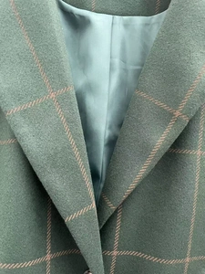 Detailed view of dark green plaid wool coat with notched lapel and smooth inner lining