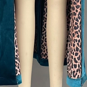 Detailed shot of dark teal velvet coat with leopard print lining and quality stitching