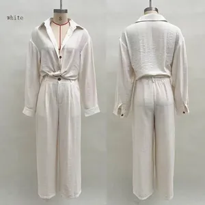 Detail of white two-piece set featuring long sleeve button shirt with tie-knot hem and pants