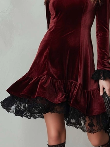 Detailed view of burgundy velvet dress featuring elegant black lace trim and ruffled hemline
