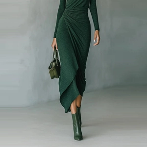 Detail of waist ruching and asymmetric cross-cut hem on a green knit dress
