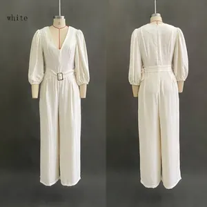 Detail of white deep V-neck jumpsuit featuring puff sleeves and belted high waist