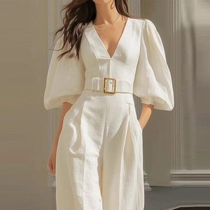 Detailed view of white V-neck jumpsuit with lantern sleeves and gold buckle waist belt