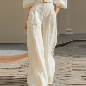 Detail of off-white high-waisted wide-leg linen trousers with a gold buckle belt