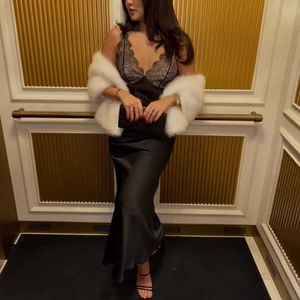 Detail of lace neckline on a black satin slip dress paired with a white faux fur shawl