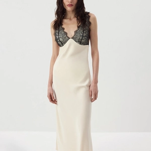 Detailed view of cream silk dress featuring black lace patchwork and a deep V-neckline