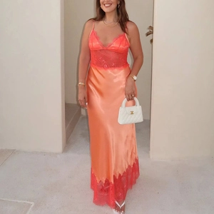 Détail de robe longue en satin corail avec bordure en dentelle rouge et col en V