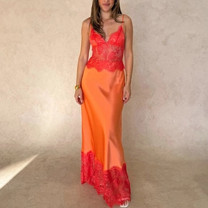 Détail de la robe longue en satin orange avec dentelle rouge contrastée et col en V chic