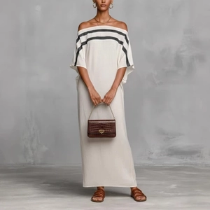 Detail view of white off-shoulder maxi dress with black stripes and summer resort texture