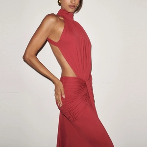 Detail of red halter neck dress featuring low back cut and ruched waist knot design