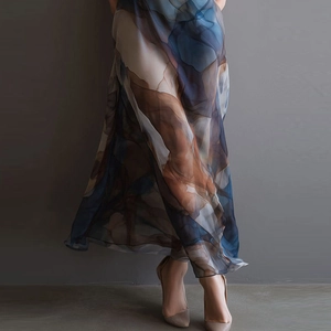 Detail of sheer mesh dress featuring blue and caramel abstract tie-dye print with flowy hem