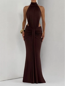 Detailed view of cutout waist design and pleated drapery on halter neck maxi dress