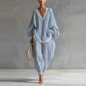 Dettaglio dei bordi in pizzo bianco su top a righe blu e pantaloni ampi coordinati