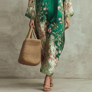 Détail de l'imprimé fleuri sur robe longue en soie verte avec sac en paille