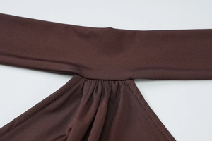 Detailed close-up of dark brown bodycon dress showing ruched halter neckline and fine stitching