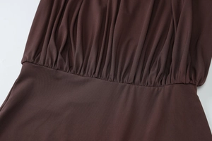 Close-up of gathered ruching details on the waist of a dark brown bodycon dress