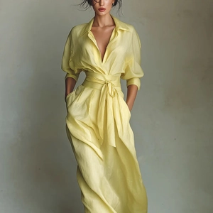 Detail of light yellow silk shirt dress featuring a deep V-neck and a matching wide waist belt