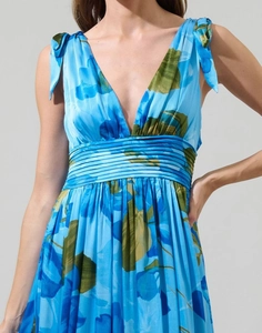 Détail du décolleté en V, nœuds d'épaule et tissu mousseline floral sur robe longue bleue