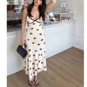 Slim fit white v-neck cami dress with black bow prints in a retro romantic style