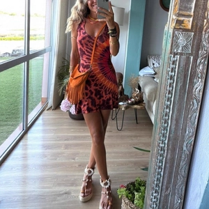 Detail of bohemian tie-dye sleeveless dress paired with orange tassel bag and wedge sandals