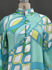 Detail of colorful geometric print dress showing the stand collar and fabric buttons