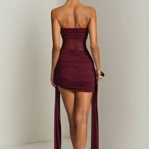 Detail of burgundy ruched tube dress featuring sheer mesh waist and elegant side streamers