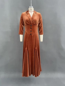 Détail d'une robe en velours avec col tailleur, boutons à la taille et ourlet plissé