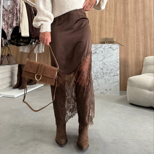 Détail de la jupe en satin et dentelle associée à un sac à main en daim marron