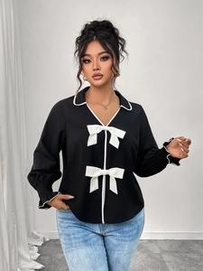 Detail of black polo collar top featuring white contrast trim and large decorative bows