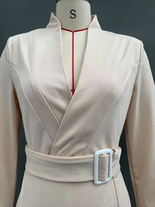Detail of elegant beige midi dress with V-neckline and resin buckle belt on mannequin